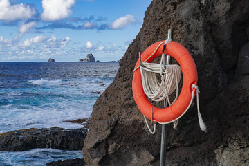 life ring with a rope, hanging next to the volcanic rocks, La Frontera, with Atlantic ocean and sky...