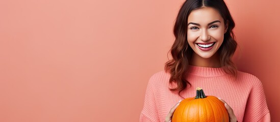 Smiling woman holding Halloween pumpkin with pink background at home - Powered by Adobe
