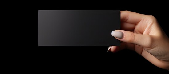 Naklejka premium Caucasian woman s hand holds black business card on black background Symbolizes business and writing space