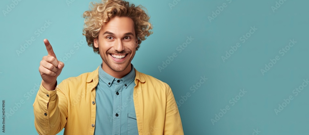 Poster happy and satisfied young man casually pointing to empty space with a cheerful smile