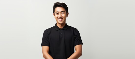 Asian male smiling and holding a blank space dressed in black polo t shirt on white background