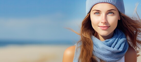 Portrait of a young Caucasian woman at the beach in August with a scarf and blue sky representing summer enjoyment and holiday concept