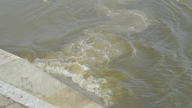 Sewage pipe outfall into the river, water pollution and environmental damage concept