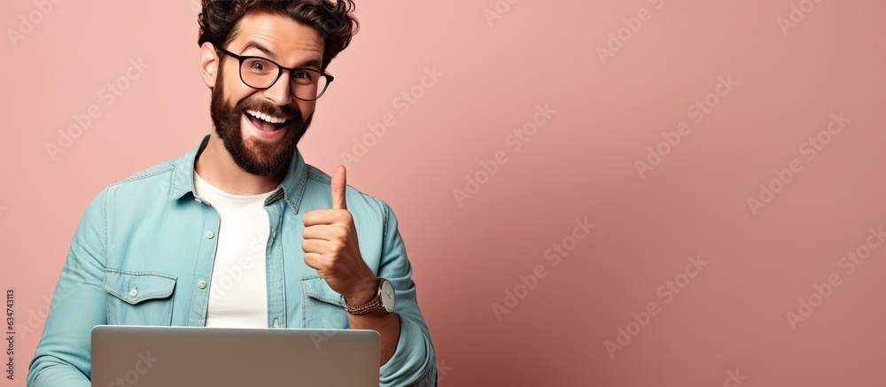 Poster A happy bearded young man with laptop smiling and pointing to the side and upwards displaying an object in empty area
