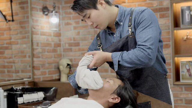 따뜻한 스팀타월로 손님의 얼굴을 닦아내는 바버샵 직원 