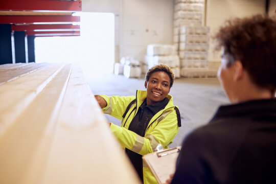 Smiling female worker discussing with colleague while working in lumber industry