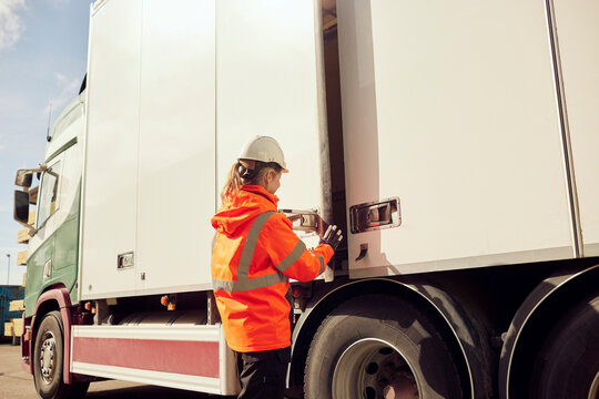 Female worker locking door of truck outside factory on sunny day