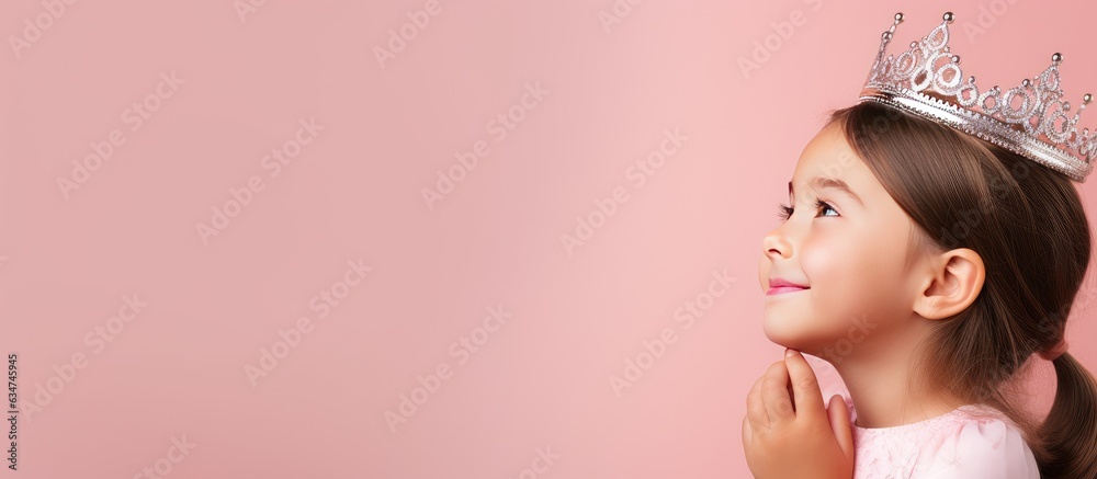 Poster happy young girl wearing toy crown posing over pink background looking aside with dreamy expression