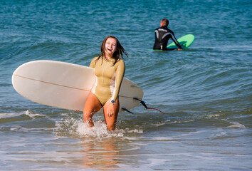 Pretty young woman surfer coming out of the ocean waves