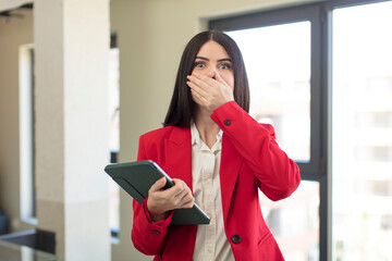 pretty young woman covering mouth with a hand and shocked or surprised expression. touch screen pad concept