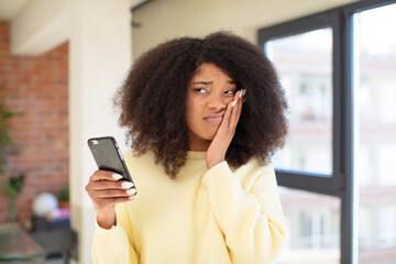 pretty afro black woman feeling bored, frustrated and sleepy after a tiresome. smartphone concept