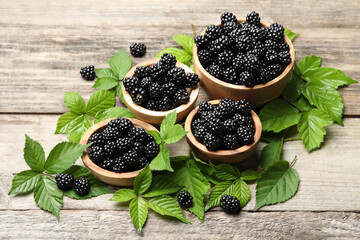 Ripe blackberries and green leaves on wooden table