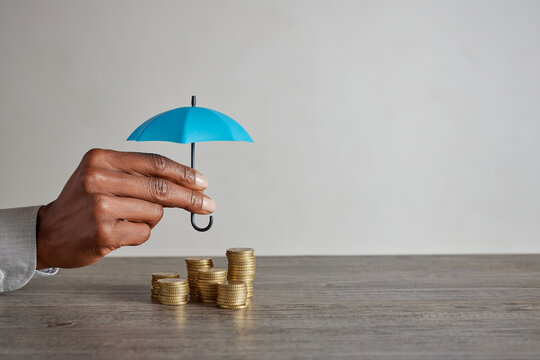 Black woman hand holding umbrella over money to protect her savings