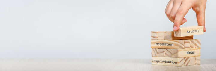 Artistry concept. The hand places the wooden rectangles next to the others, wooden cubes with the...