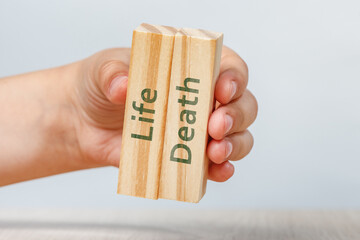 Life and Death. The hand holds two wooden cubes with inscriptions close-up. Isolate of rectangles...