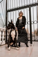 A woman walks with her Great Dane in an urban setting, enjoying the outdoors and the company of her...