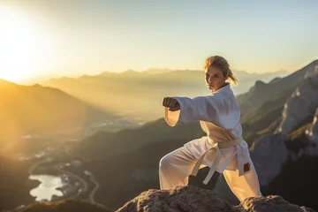 Deurstickers Woman practicing martial arts on the top of a mountain. Generative AI © YouraPechkin