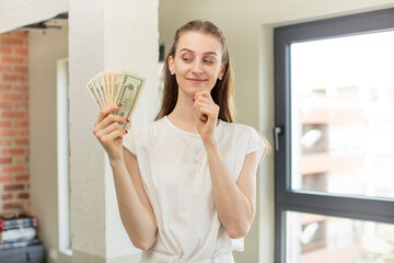 smiling with a happy, confident expression with hand on chin. dollar banknotes concept