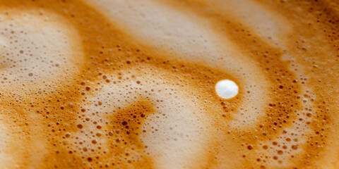 Cappuccino milk foam spiral close-up. Background texture of foam with bubbles of whipped milk in coffee.