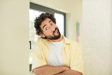 Fototapeta premium young crazy bearded man shrugging, feeling confused and uncertain, doubting with arms crossed and puzzled look