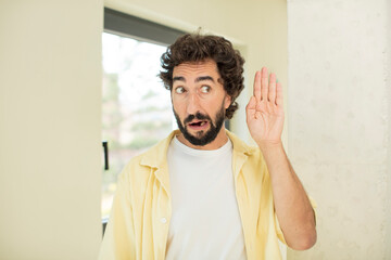 young crazy bearded man looking serious and curious, listening, trying to hear a secret...