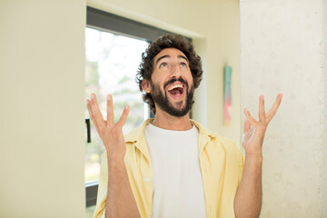 young crazy bearded man feeling happy, amazed, lucky and surprised, celebrating victory with both hands up in the air