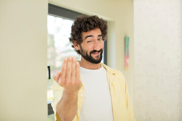Fototapeta premium young crazy bearded man feeling happy, successful and confident, facing a challenge and saying bring it on! or welcoming you
