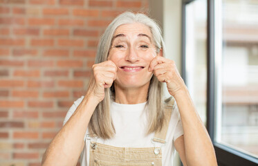 senior pretty woman smiling and pointing to own fake smile