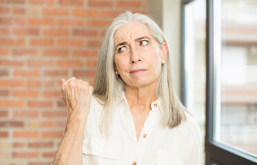 senior pretty woman looking confident, angry, strong and aggressive, with fists ready to fight in boxing position