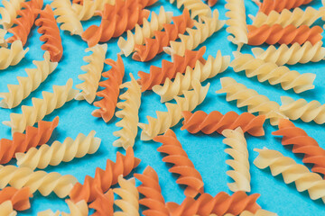 Set of scattered two-colored pasta on blue background. Close-up. Macro.