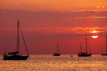 Red orange sunset on the sea with silhouette of yachts