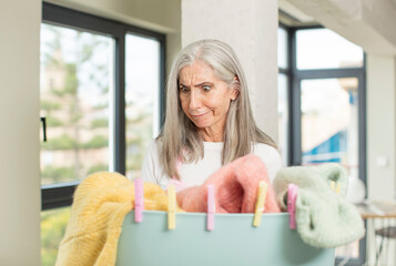 pretty senior woman smiling and looking with a happy confident expression. washing clothes concept