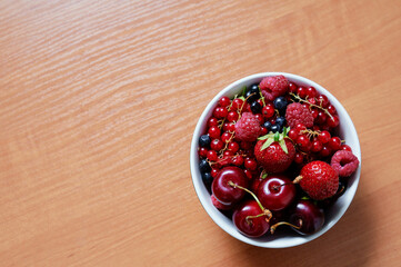 Strawberries, cherries, currant on the wooden surface.