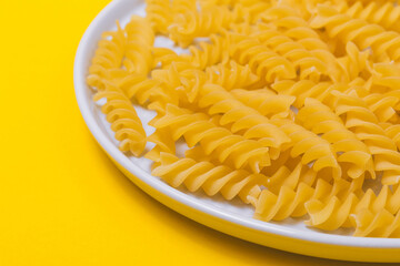 Yellow pasta in the plate on yellow background. 