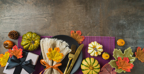 Thanksgiving party banner concept with  plate, pumpkin and autumn leaves on dark background. Top...