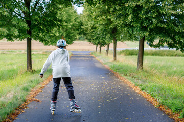 Active school boy skating in summer park, healthy lifestyle for children. Happy teenager with...