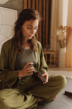 Young Woman holding Tarot cards and sitting in lotus pose on yoga mat, relaxed with closed eyes. Mindful meditation concept. Wellbeing. No focus blurred and noise effect