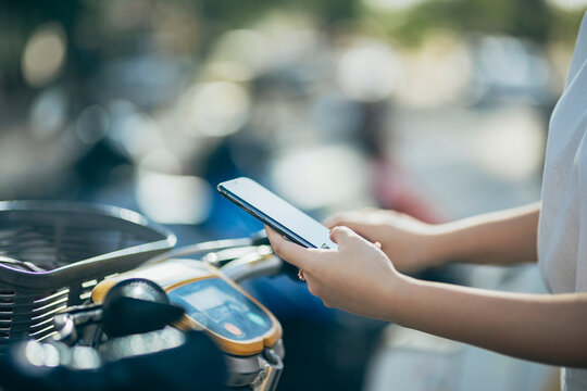Asian women are utilizing their smartphones to rent shared bicycles for their daily commutes. With a few taps on their screens, they unlock the bikes and set off on their eco-friendly journey.