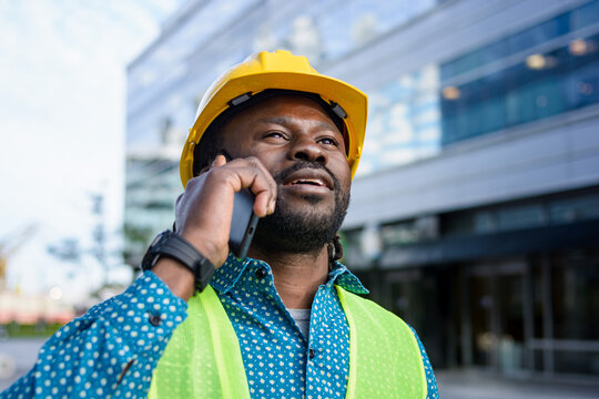African ethnicity civil engineer man outdoors talking on phone looking up