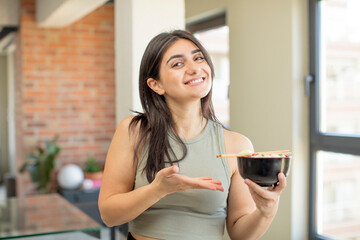 young woman smiling cheerfully, feeling happy and showing a concept. ramen bowl