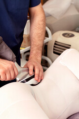 Close-up strong male hands do LPG massage female body lies on its side in a white suit with anti-cellulite LPG massage. Weight loss and LPG complex massage