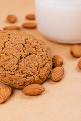Oatmeal cookies, glass of milk and almonds on beige background.