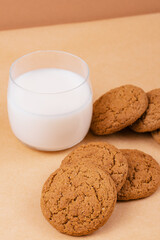 Oatmeal cookies and glass of milk on beige background.