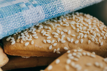 Close-up of freshly baked homemade biscuits with sesame covered by towel. 