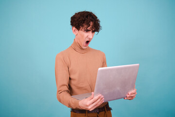 Funny curly student is studying. Attractive guy posing on a blue background.