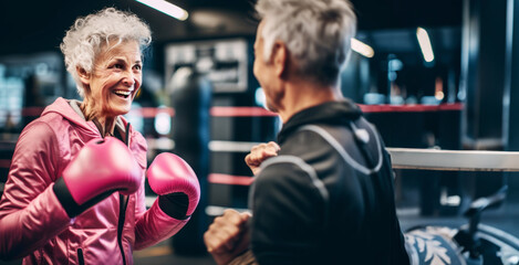 Senior woman boxer, displaying vitality and resilience, practicing with her coach. A confident expression of strength, active exercise, challenging stereotypes.