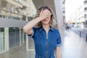 Fototapeta premium pretty woman covering eyes with one hand feeling scared or anxious, wondering or blindly waiting for a surprise