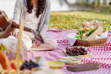 In love couple enjoying picnic time playing guitar in park outdoors Picnic. happy couple relaxing...