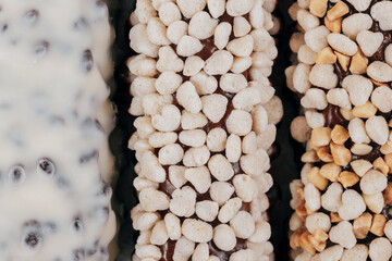Sweet chocolate bars coated with corn cereals, peanuts pieces and  white icing. Macro shot. Top view.