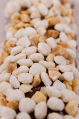 Macro shot of sweet chocolate bars coated with corn cereals and peanuts pieces.